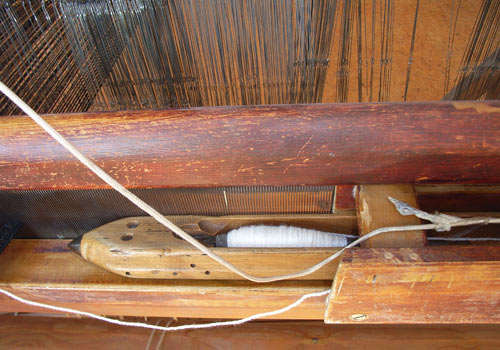 Das Schiffchen transportiert den Schussfaden durch die Kette.